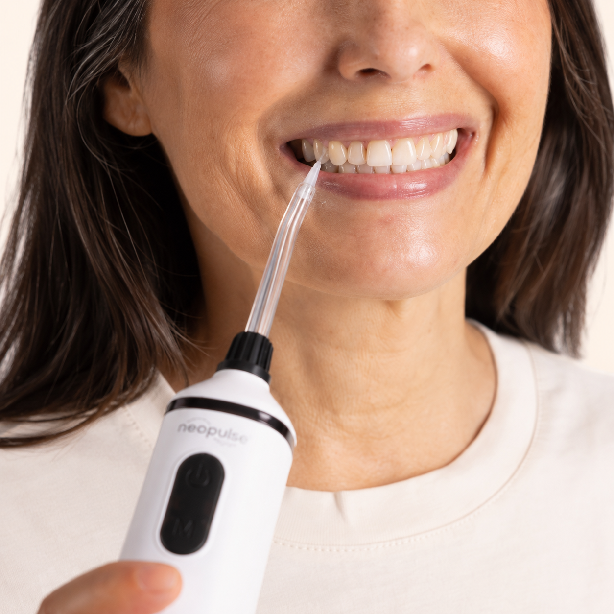 Femme utilisant une canule parodontale NEOPULSE avec un jet dentaire pour nettoyer entre les dents