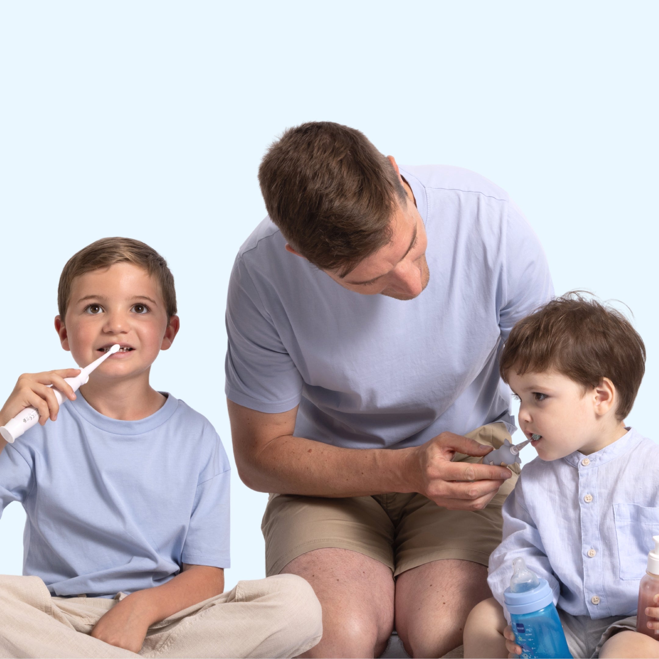 Père accompagnant deux enfants qui tiennent une brosse à dents NEOKIDS et une brosse à dents NEOBABY pour un brossage quotidien