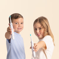 Deux enfants tenant des brosses à dents électriques NEOKIDS pour une routine de brossage ludique